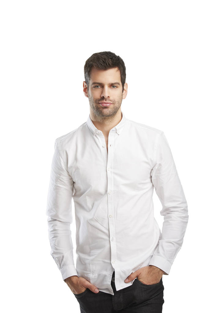 Расслабленный молодой бизнесмен в рубашке, стоя на изолированном белом фоне с копировальным пространством
.  - Фото, изображение
