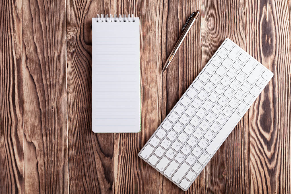 біла блокнот і комп'ютерна клавіатура на дерев'яній стільниці
 - Фото, зображення