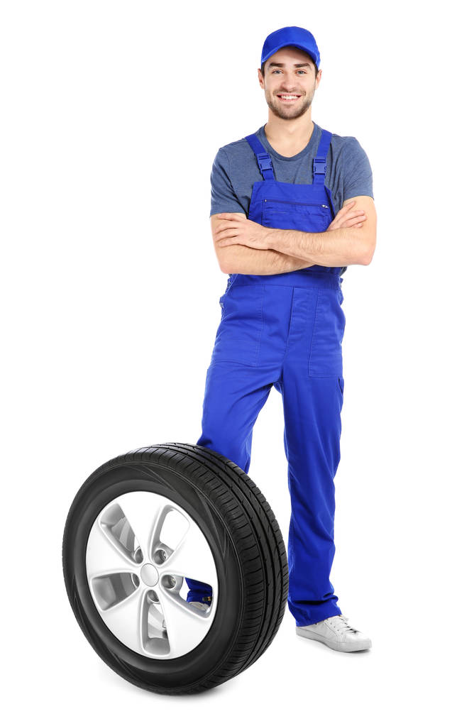 Joven mecánico en uniforme con neumático de coche sobre fondo blanco
 - Foto, imagen