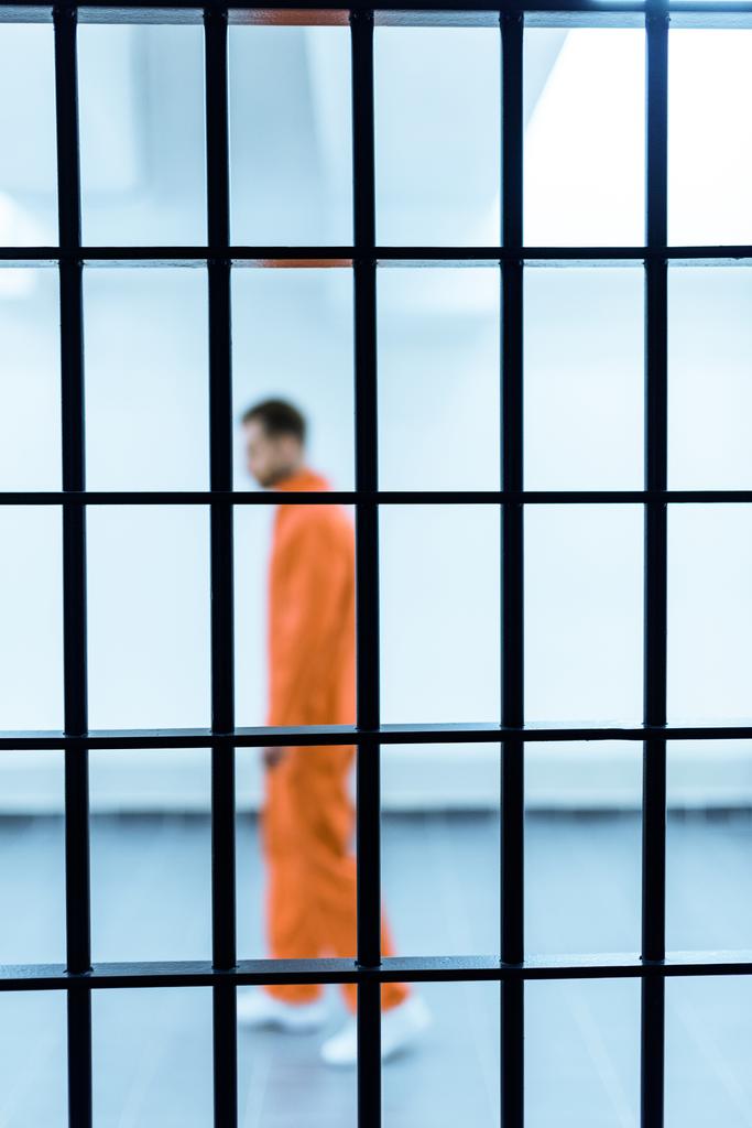 vista lateral del prisionero parado detrás de las rejas
 - Foto, imagen