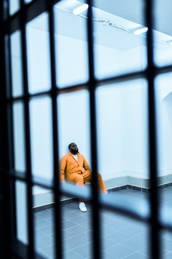 Afro-Amerikan mahkûm hapishane hücresinde bankta oturmuş - Fotoğraf, Görsel