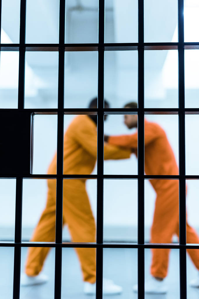 oldalnézet többnemzetiségű foglyok fenyegető egymást börtönben rács mögött - Fotó, kép