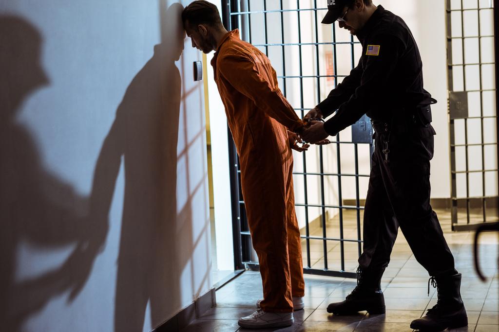 Seitenansicht eines Gefängnisbeamten, der Handschellen an Gefangenen trägt - Foto, Bild
