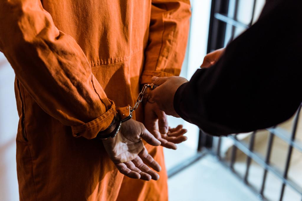levágott kép a börtönőr bilincs rajta a fogoly - Fotó, kép