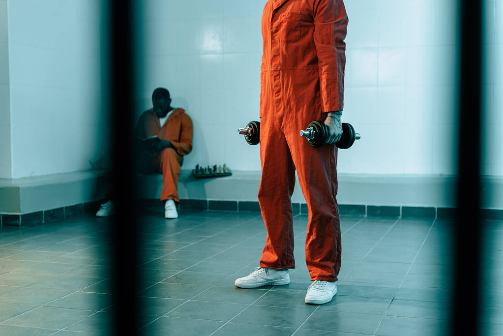 abgeschnittenes Bild vom Gefangenentraining mit Hanteln im Gefängnisraum - Foto, Bild