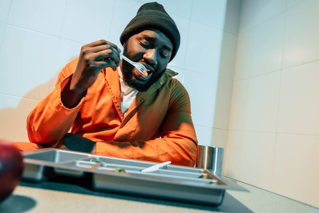 Afrikanisch-amerikanischer Sträfling isst in Gefängniszelle - Foto, Bild