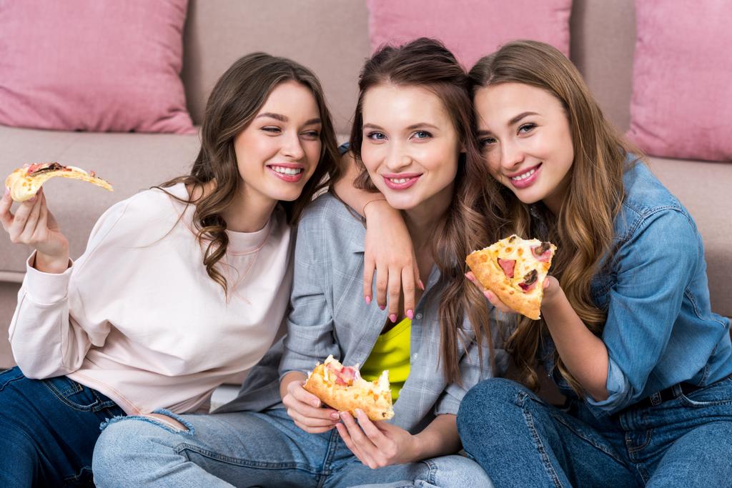 kauniit nuoret naiset syövät pizzaa ja hymyilevät kameralle
 - Valokuva, kuva