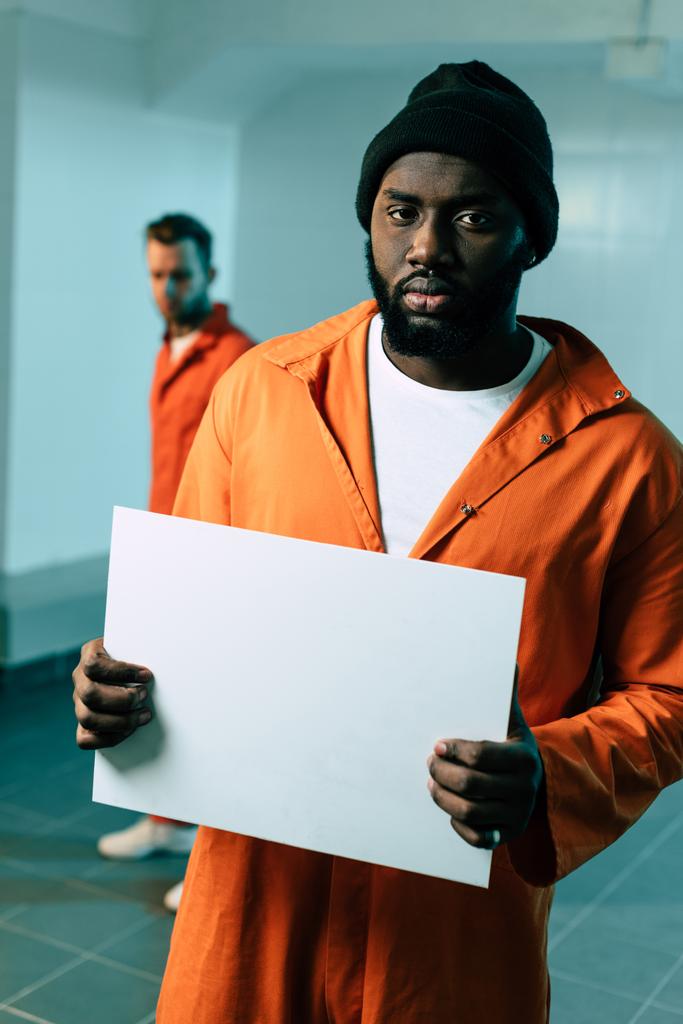 prisonnier afro-américain tenant une pancarte vierge et regardant la caméra
 - Photo, image