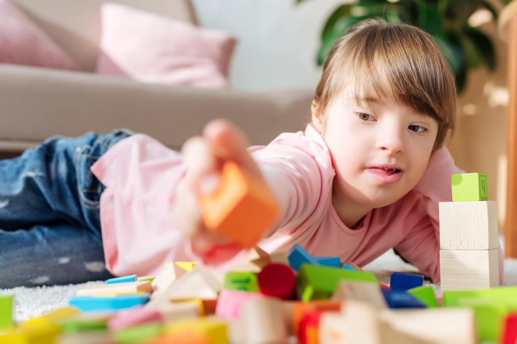 Criança com síndrome de down edifício com cubos de brinquedo
 - Foto, Imagem