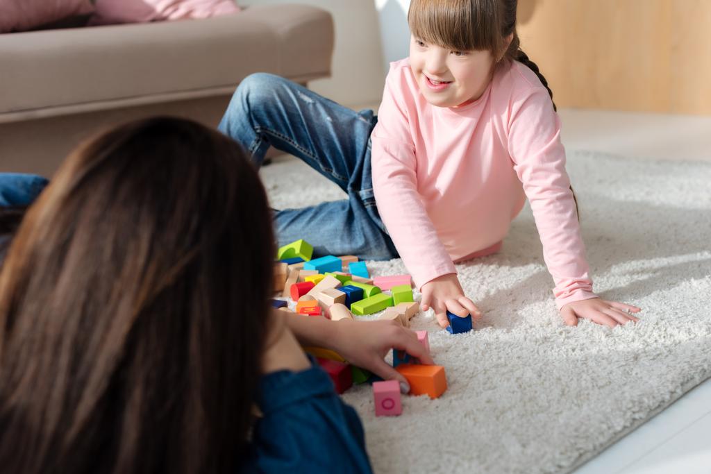 Fille avec le syndrome du duvet et sa mère jouant avec des cubes de jouets
 - Photo, image