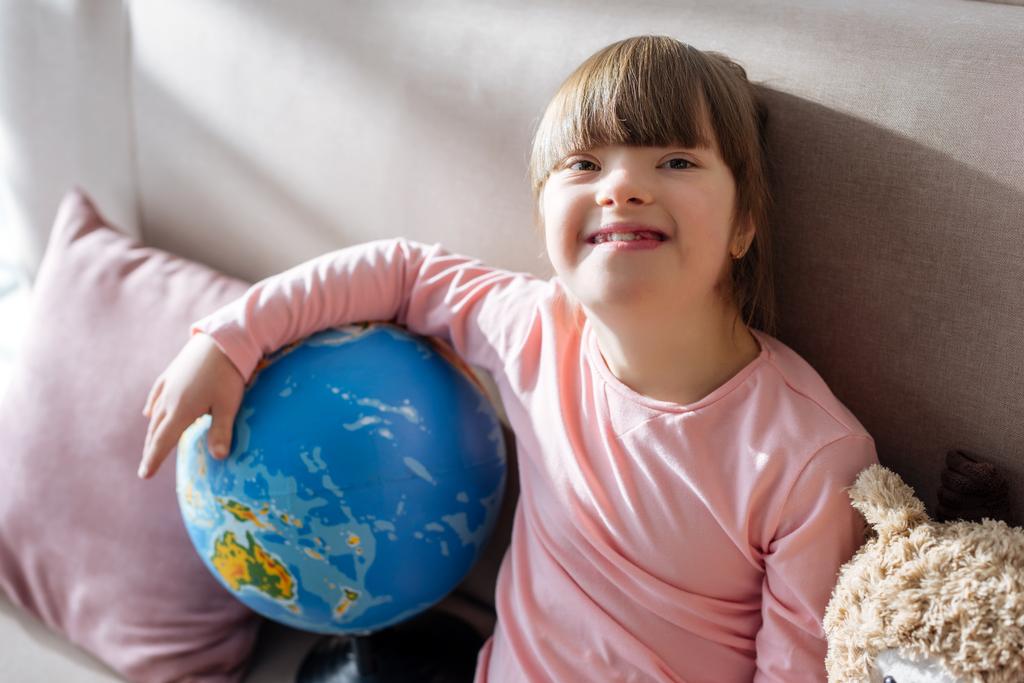 Uśmiechający się dziecko z zespołem Downa, trzymając globe - Zdjęcie, obraz