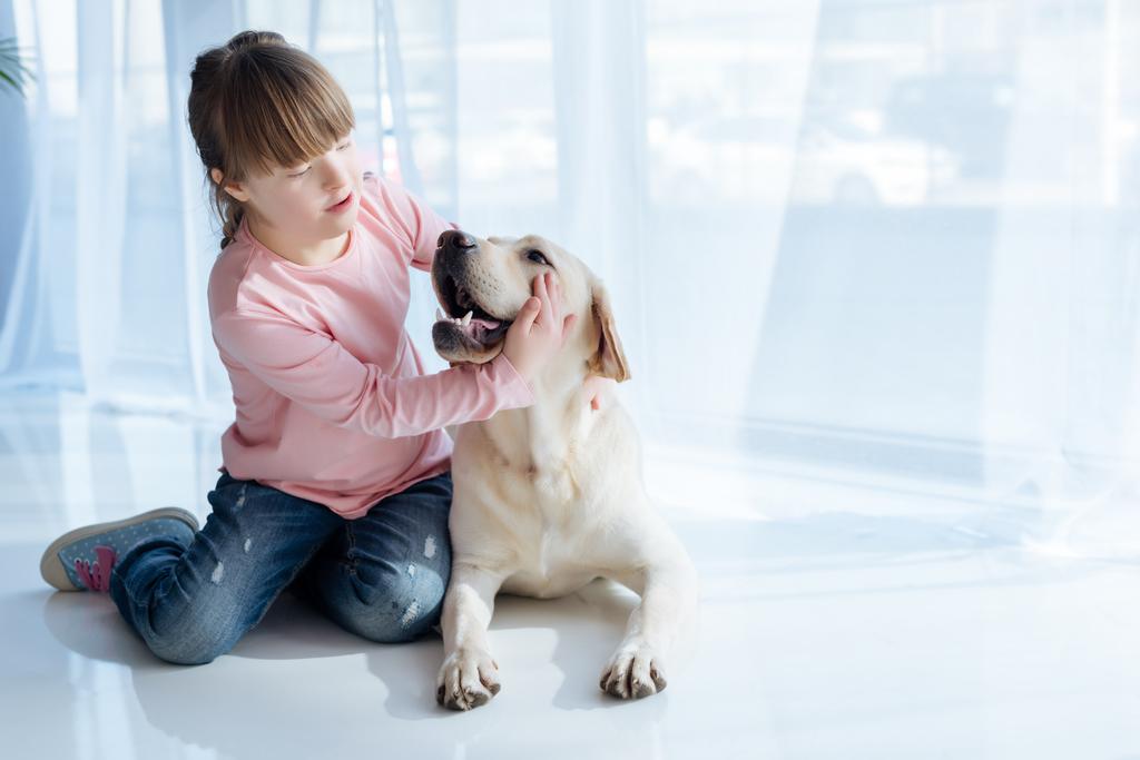 Kind mit Down-Syndrom spielt mit Labrador-Retriever  - Foto, Bild