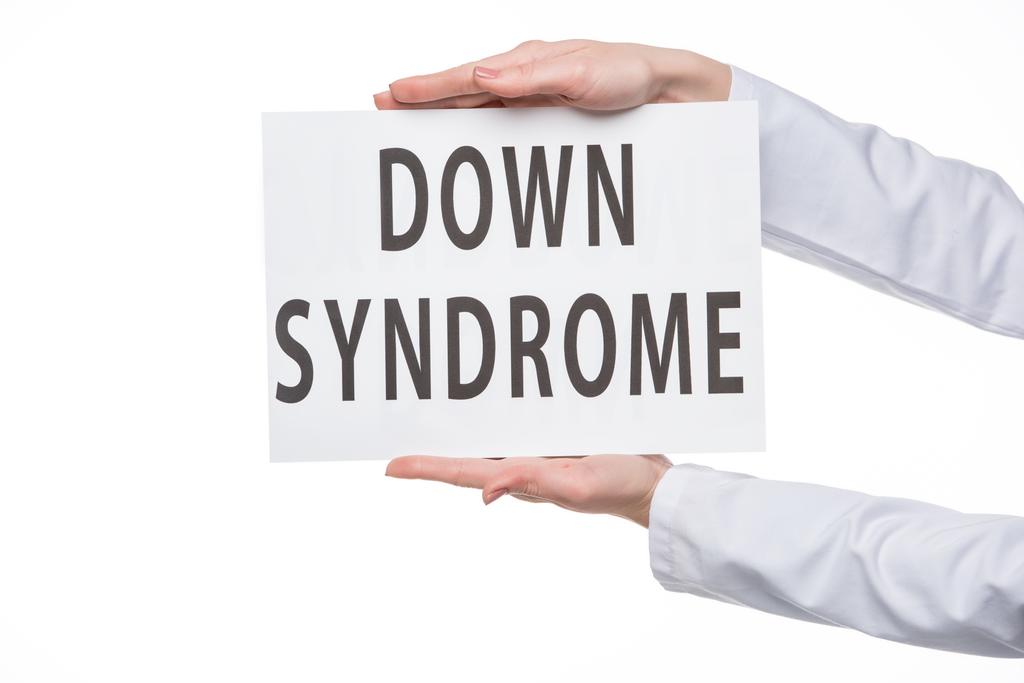Kobiece ręce trzymając znak z Down Syndrome tekst na białym tle  - Zdjęcie, obraz