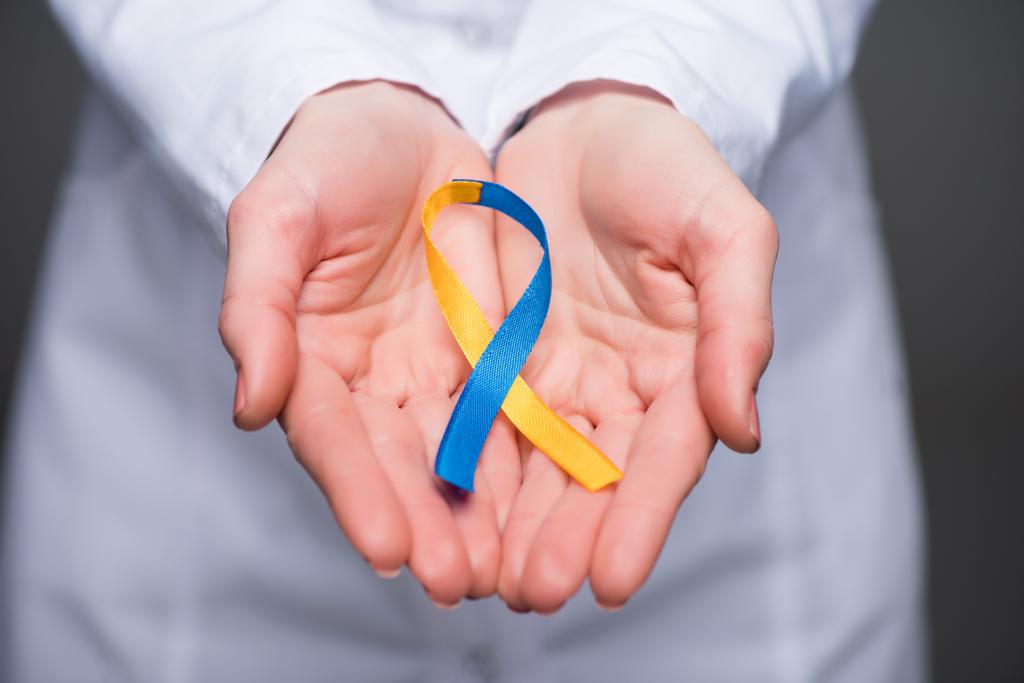 Vista de cerca de las manos del médico femenino sosteniendo la cinta del Día del Síndrome de Down
  - Foto, imagen