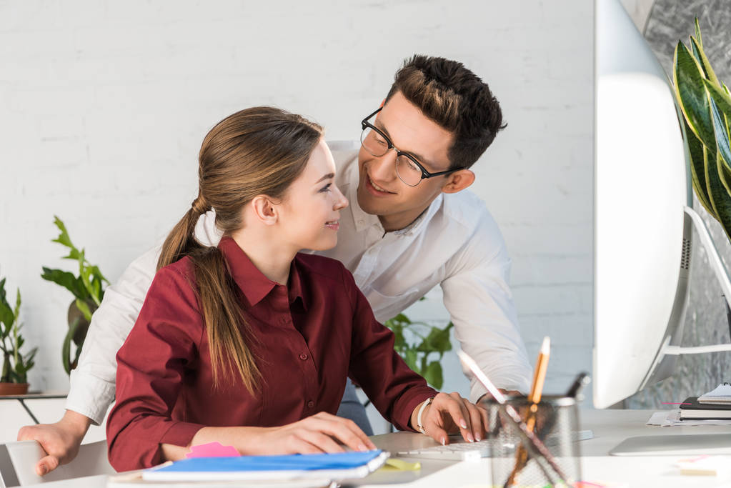 nuori komea liikemies flirttailee naispuolisen kollegansa kanssa työpaikalla modernissa toimistossa
 - Valokuva, kuva