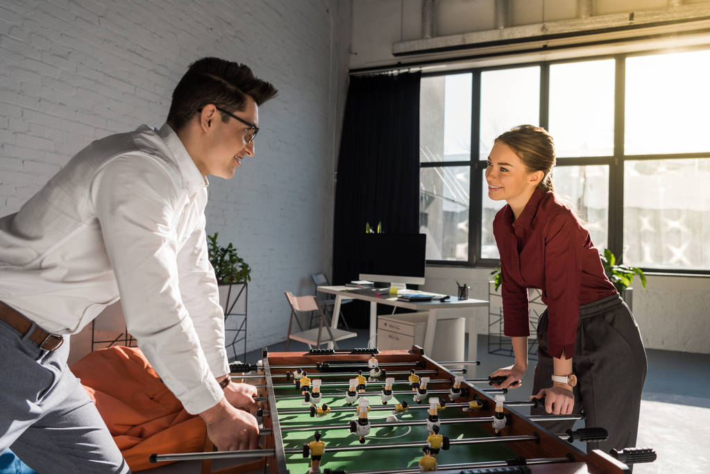 jóvenes socios de negocios jugando futbolín en la oficina moderna
 - Foto, Imagen