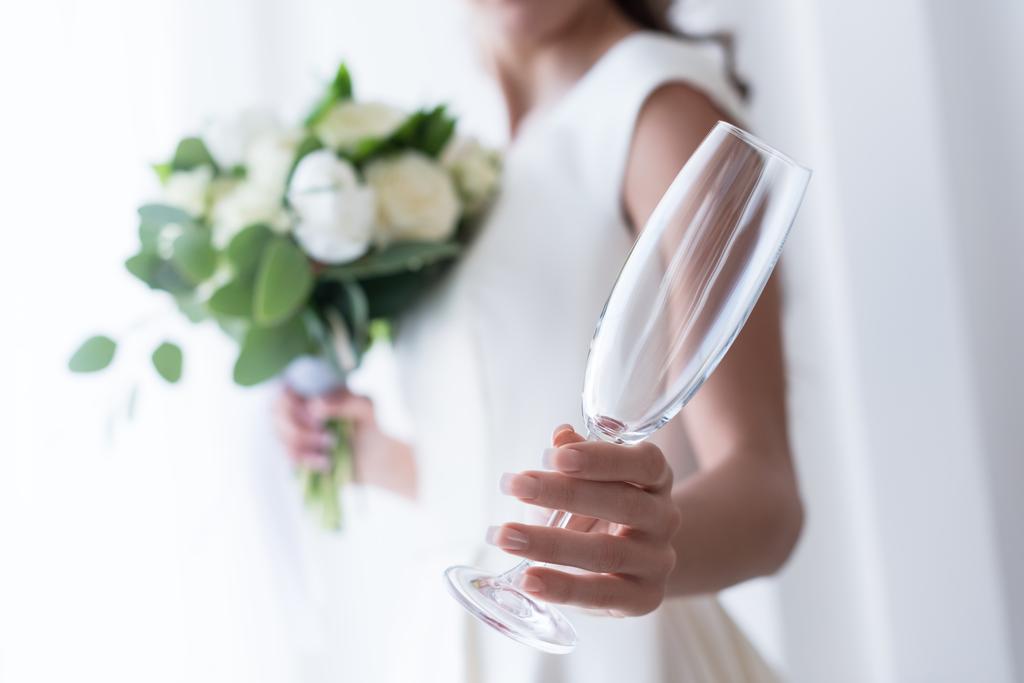 selective focus of bride with wedding bouquet holding empty champagne glass - Photo, Image
