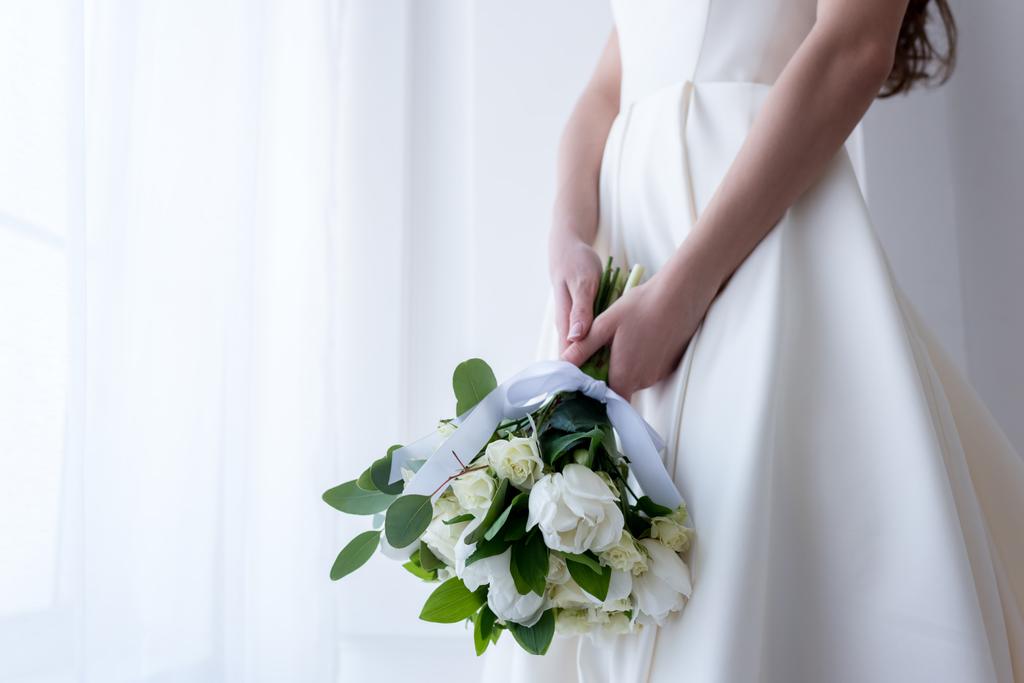 oříznutý pohled nevěsty v tradičním kroji drží svatební kytice - Fotografie, Obrázek