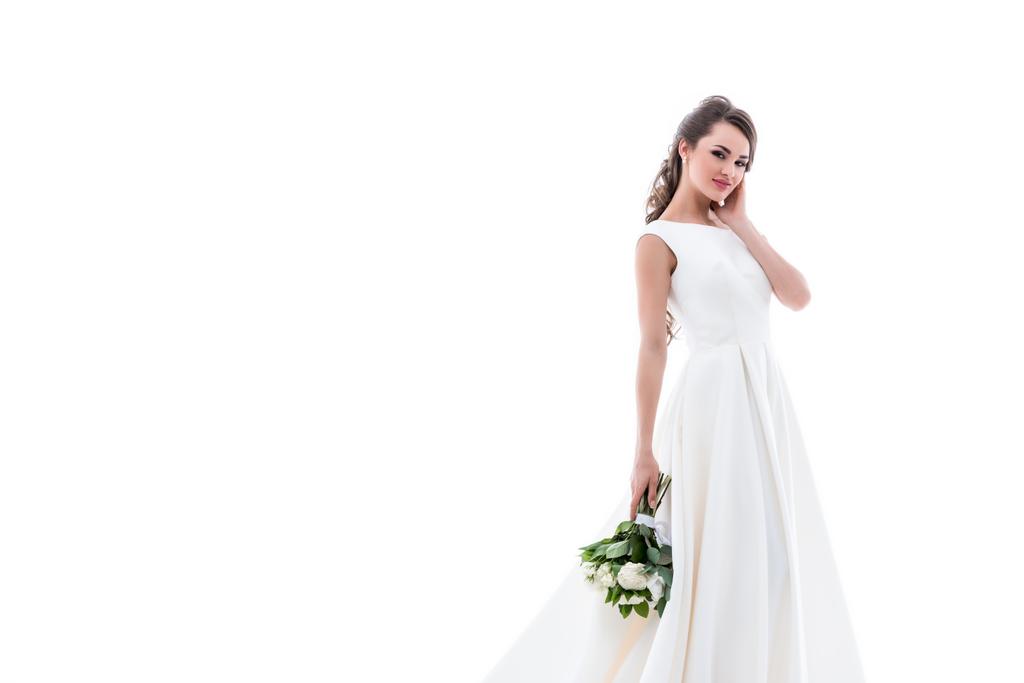 s úsměvem pózuje v tradiční bílé šaty s svatební kytici nevěsty, izolované na bílém - Fotografie, Obrázek