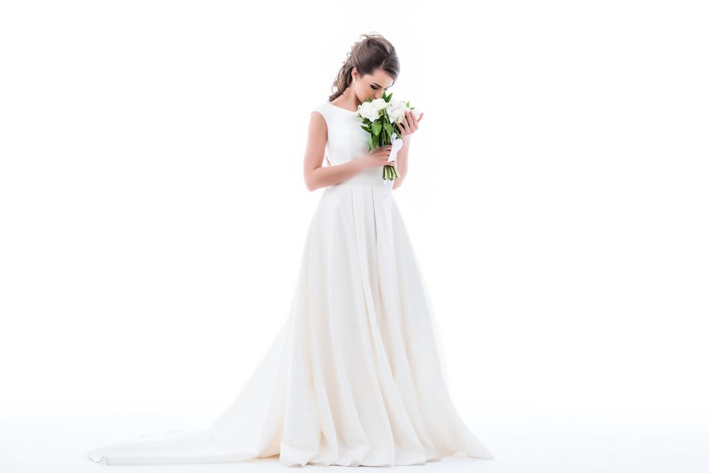 novia elegante posando en vestido tradicional y olfateando ramo de boda, aislado en blanco
 - Foto, imagen