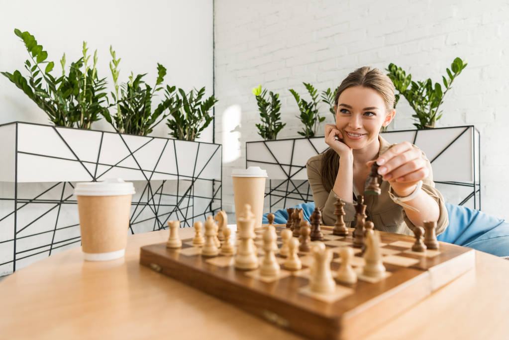 κοντινή λήψη ενός χαμογελώντας νεαρή γυναίκα παίζει σκάκι - Φωτογραφία, εικόνα
