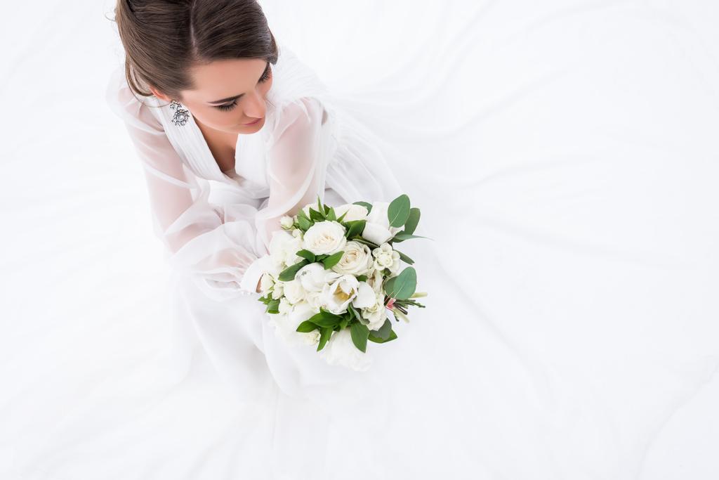 Εναέρια άποψη του νεαρή νύφη σε εκμετάλλευση γαμήλια ανθοδέσμη, απομονώνονται σε λευκό φόρεμα - Φωτογραφία, εικόνα