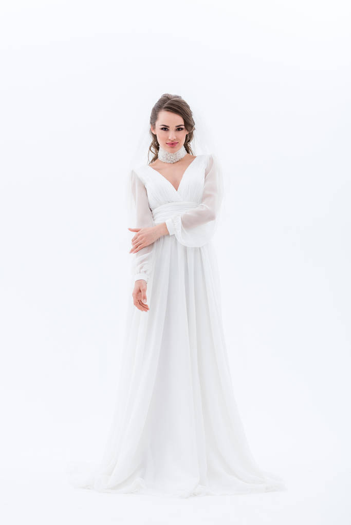 schöne lächelnde Braut posiert in traditionellem Hochzeitskleid, isoliert auf weiß - Foto, Bild