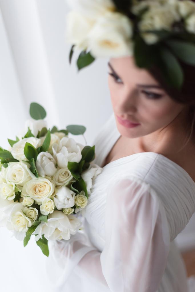 επιλεκτική εστίαση του νεαρή νύφη στο floral στεφάνι με την ανθοδέσμη γάμου  - Φωτογραφία, εικόνα
