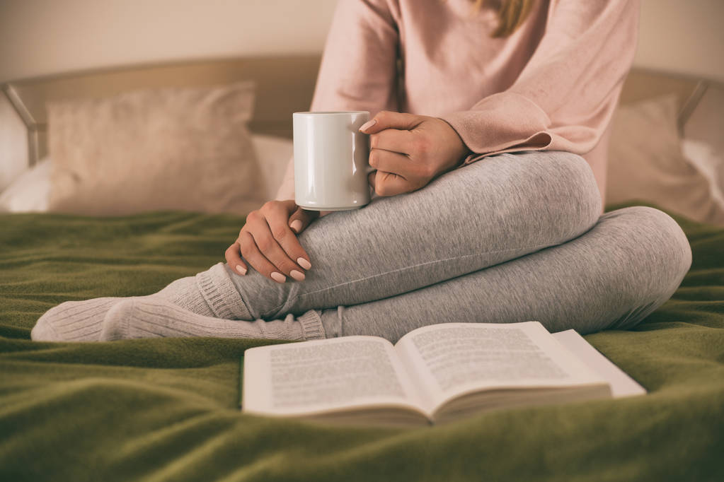 Фото женщины, отдыхающей во время чтения книги и питья кофе. Изображение намеренно тонизируется
. - Фото, изображение