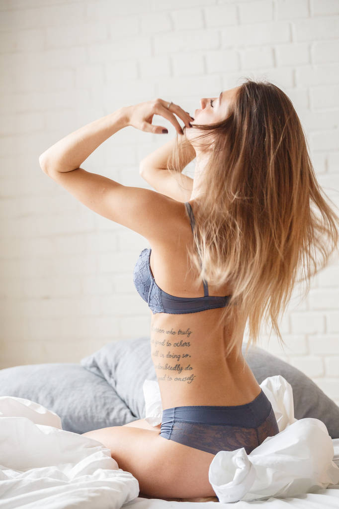 bella donna bruna in biancheria intima blu sexy in posa in camera da letto luminosa
  - Foto, immagini