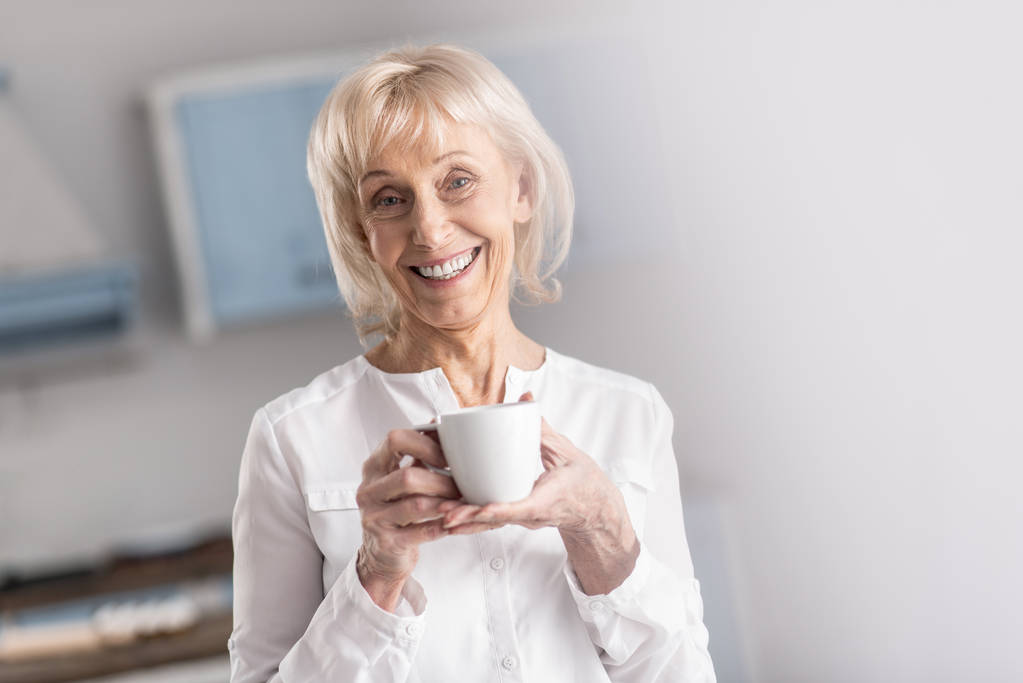 fröhliche reife Frau trinkt Kaffee - Foto, Bild