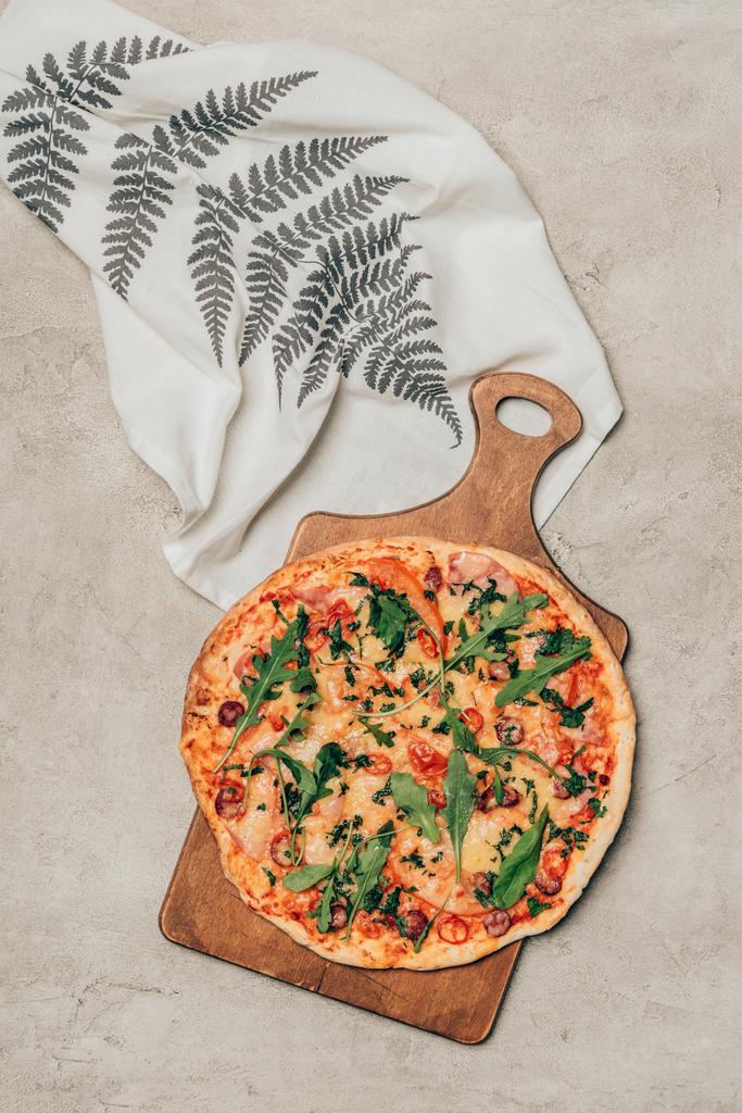 Vynikající pizza na dřevěném prkénku s ubrouskem na světlé pozadí - Fotografie, Obrázek