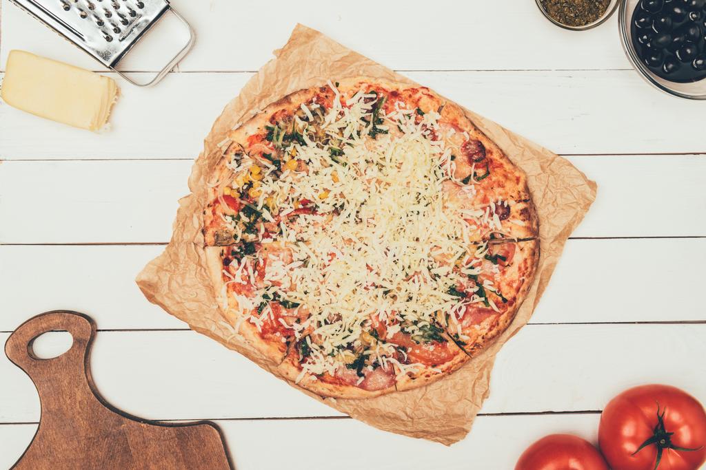 Pizza con ingredientes de cocina sobre fondo de madera blanca
 - Foto, imagen