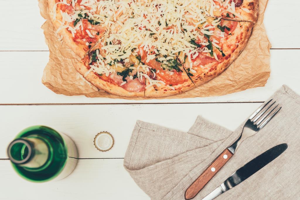Pizza italiana y botella abierta sobre fondo blanco de madera
 - Foto, Imagen