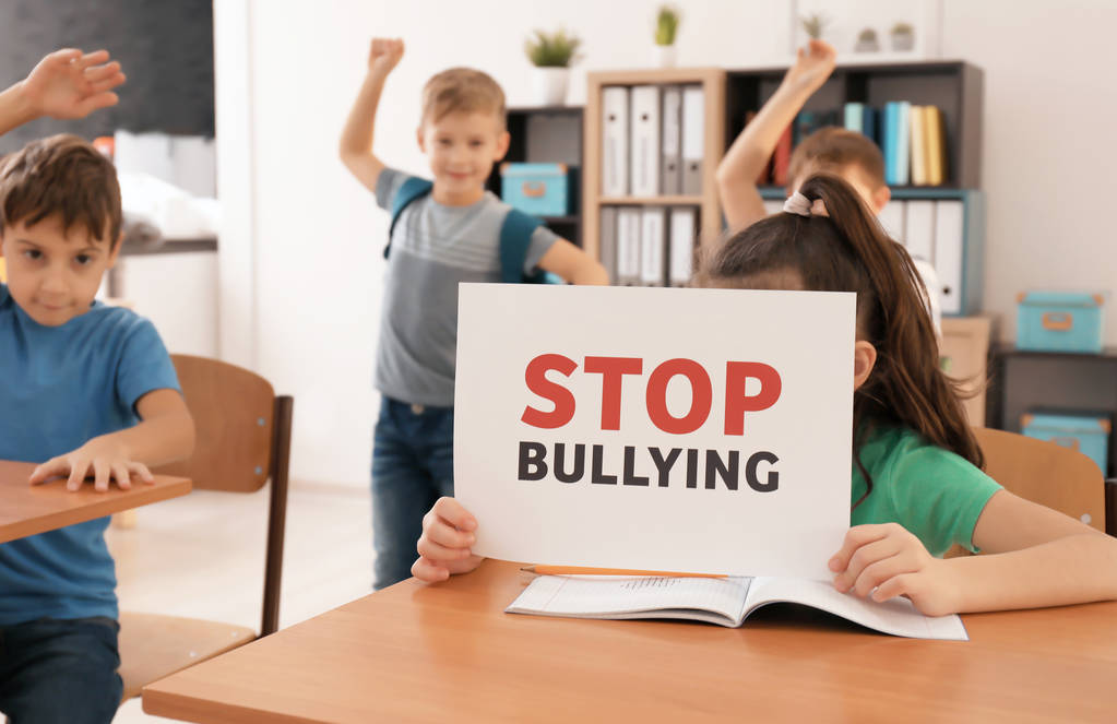 Bambina con cartello "Stop al bullismo" in classe
 - Foto, immagini