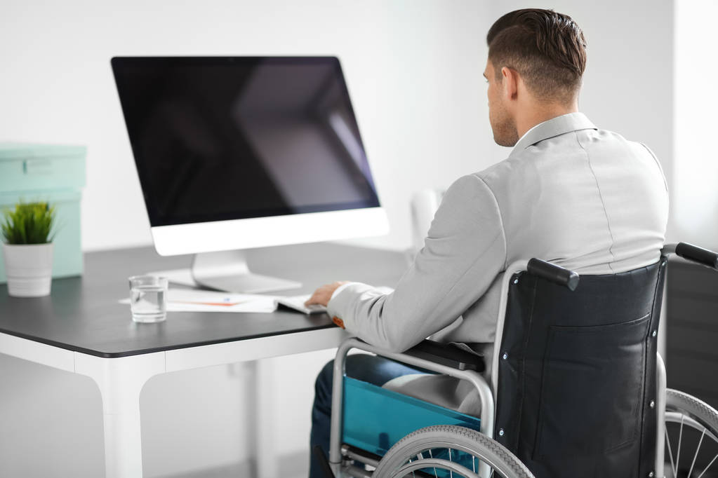 Jeune homme en fauteuil roulant sur le lieu de travail
 - Photo, image