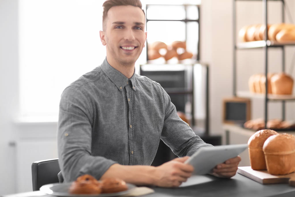 Young man using tablet computer in bakery. Small business owner - Photo, Image