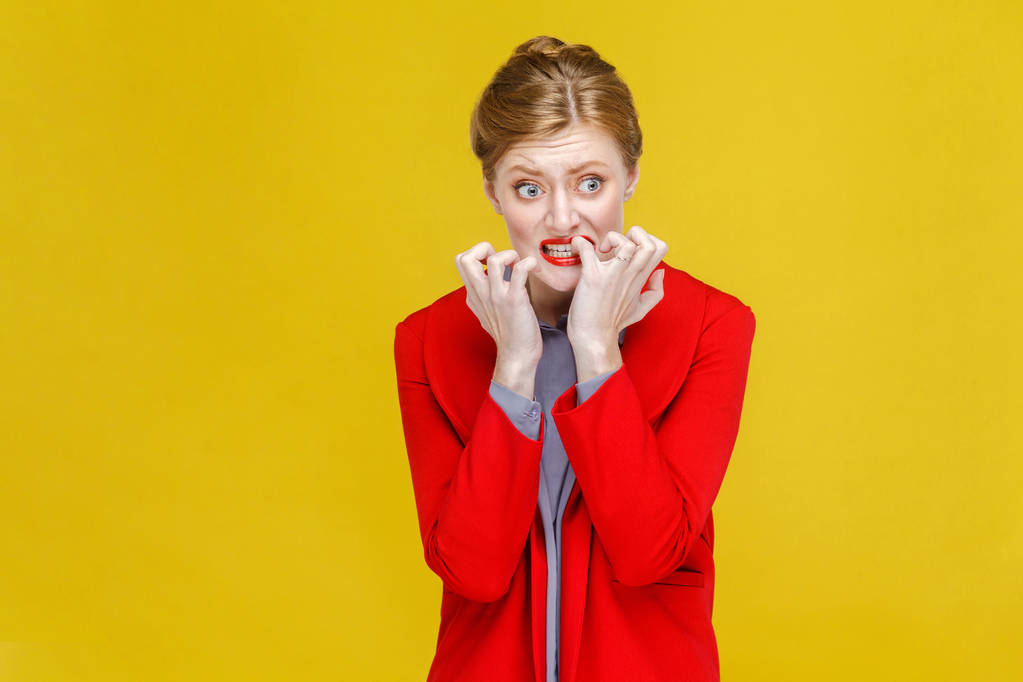 worry businesswoman gnawing nails and looking at camera with hope on yellow background - Photo, Image