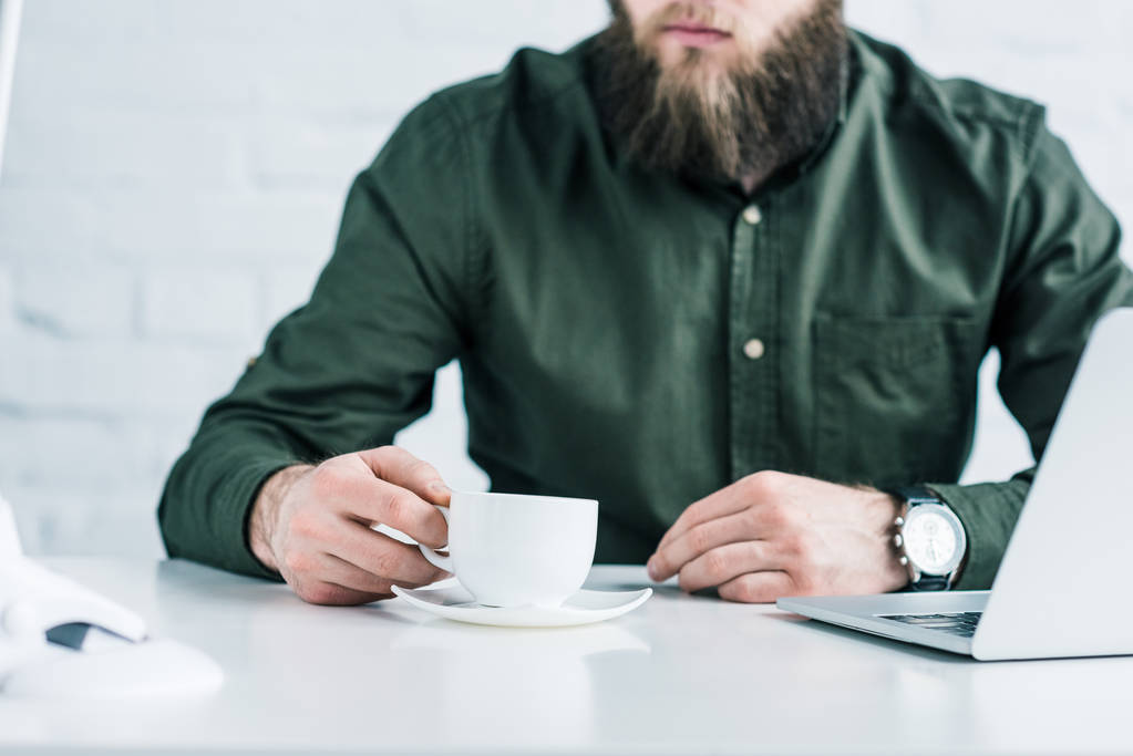 recortado tiro de hombre de negocios con taza de café en el lugar de trabajo
 - Foto, Imagen