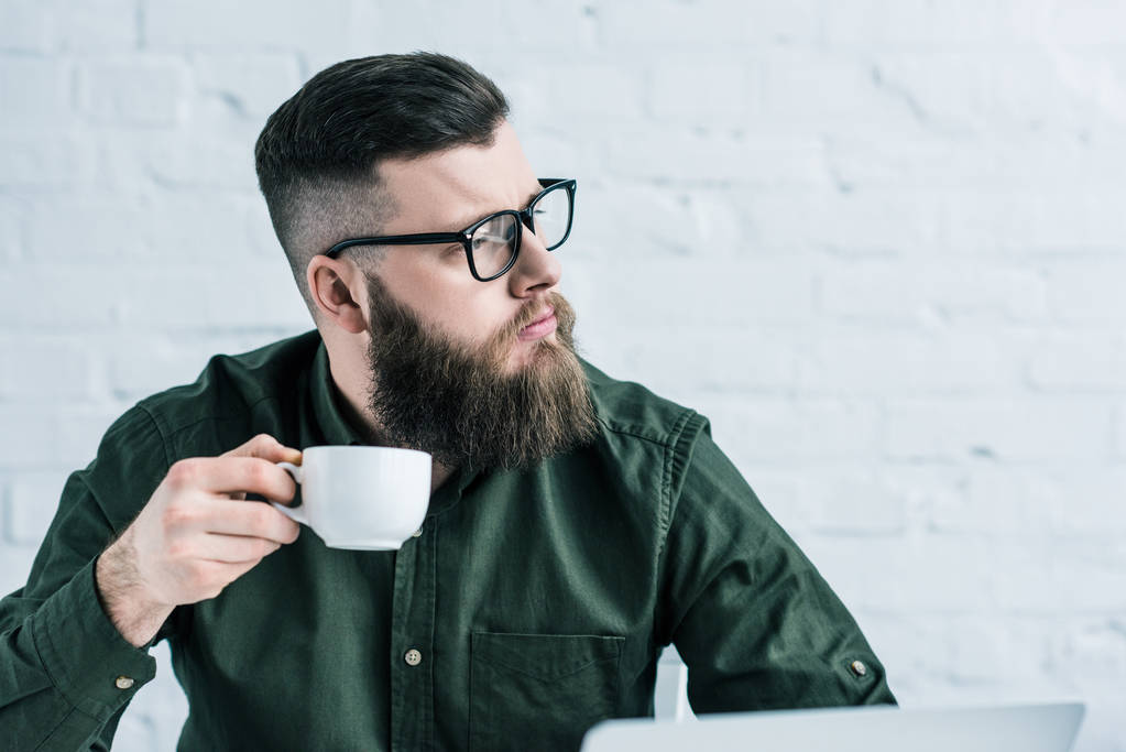 portrait of pensive businessman holding cup of coffee in hand - Photo, Image