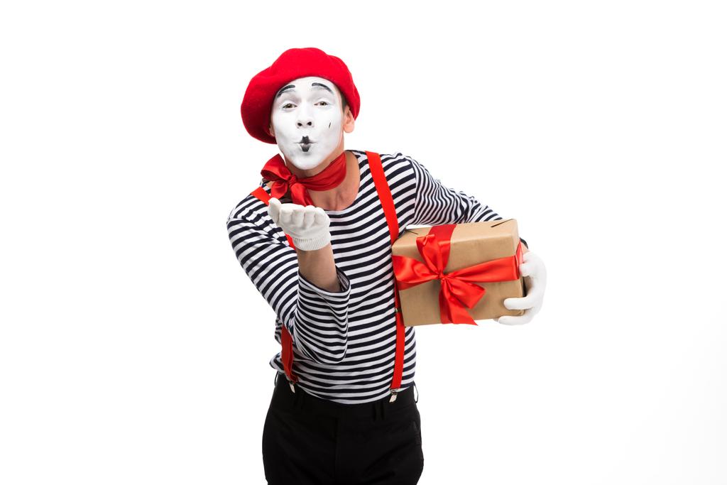 Pantomime hält Geschenkbox und sendet Luftkuss isoliert auf weiß - Foto, Bild
