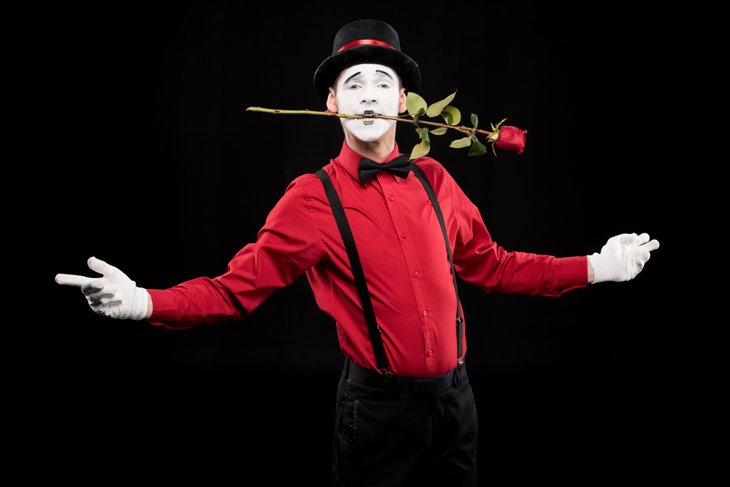 Mime hält rote Rose im Mund und steht mit offenen Armen isoliert auf schwarz - Foto, Bild