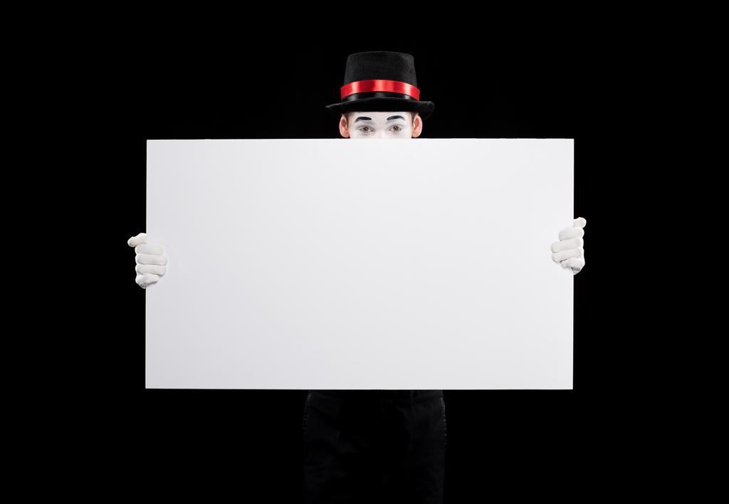 mime looking out from empty board isolated on black - Photo, Image