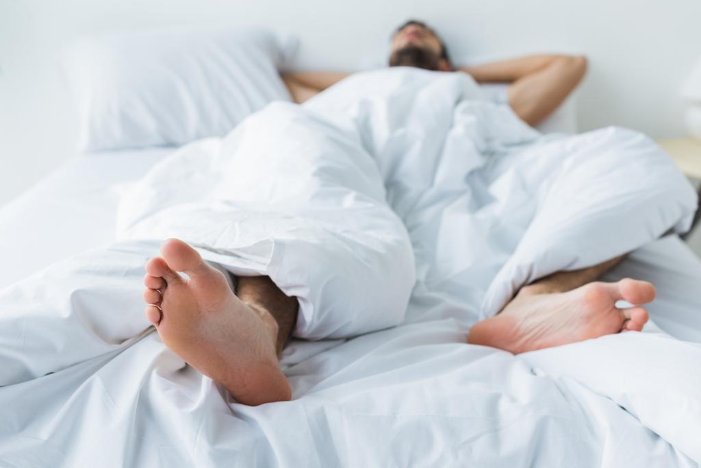 szelektív összpontosít az ember alszik, ágyon, előtérben a láb  - Fotó, kép