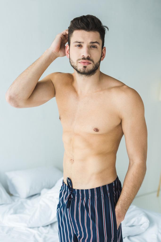 bell'uomo senza camicia in piedi in camera da letto al mattino
 - Foto, immagini