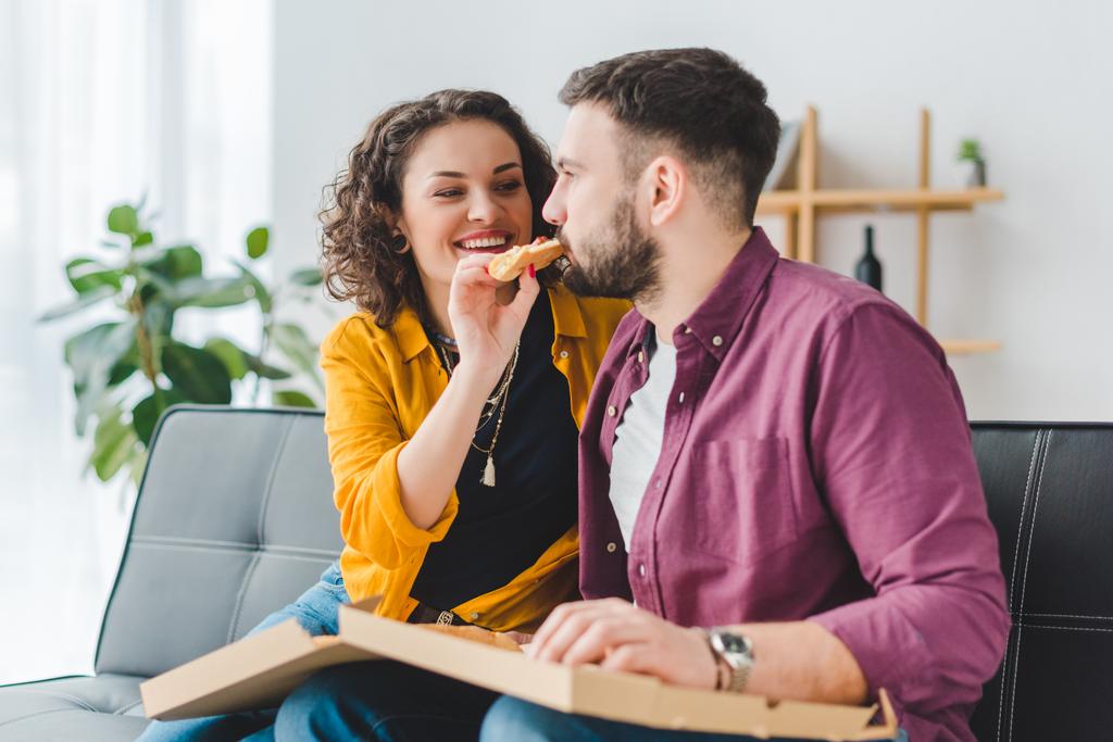 Hymyilevä nainen ruokkii poikaystävänsä pizzalla
  - Valokuva, kuva