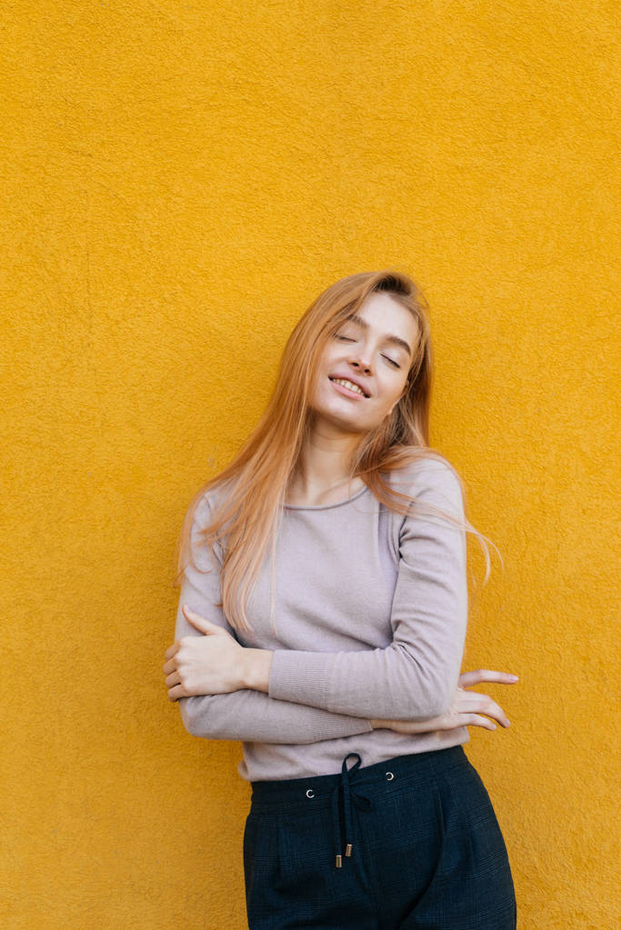krásná mladá blondýnka dívka pózuje na pozadí žluté zdi, s úsměvem, pouliční styl - Fotografie, Obrázek