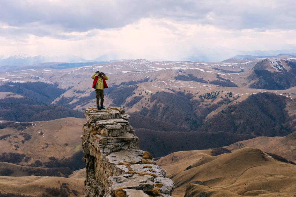 Un viajero masculino en una chaqueta viaja a través de las montañas, disfruta de la naturaleza y el aire limpio
 - Foto, Imagen