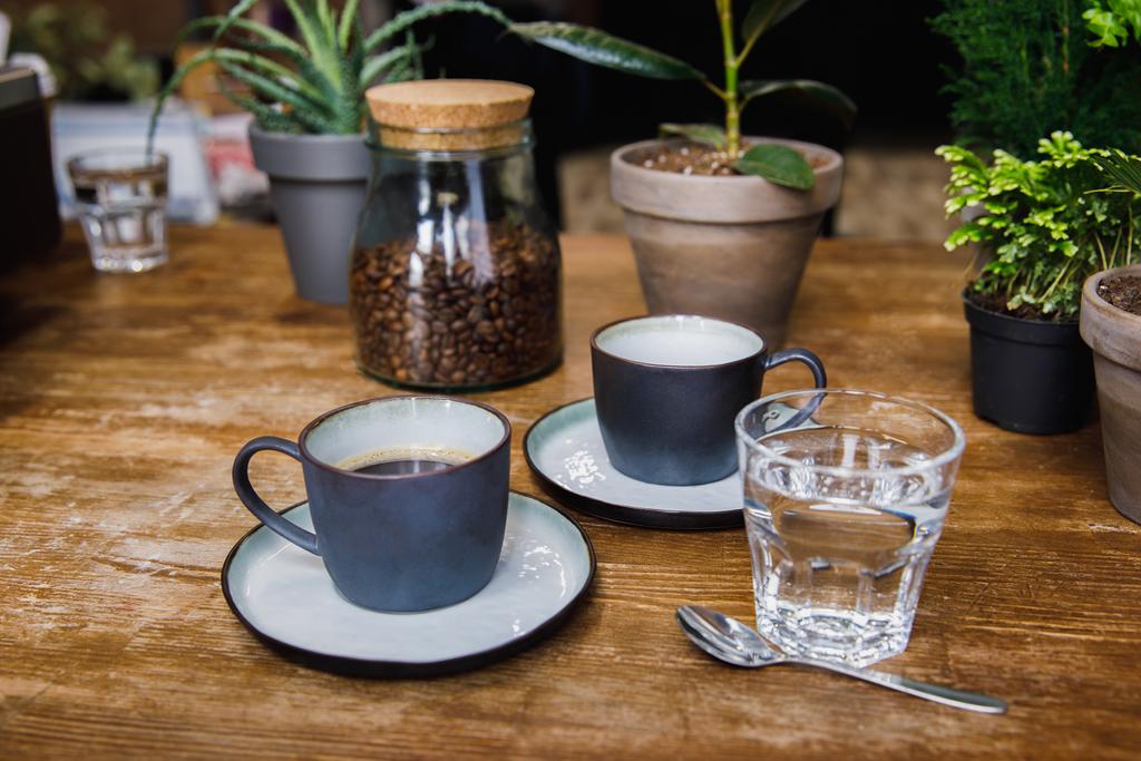 Cups of coffee and glass of water on table in cozy coffee shop - Photo, Image
