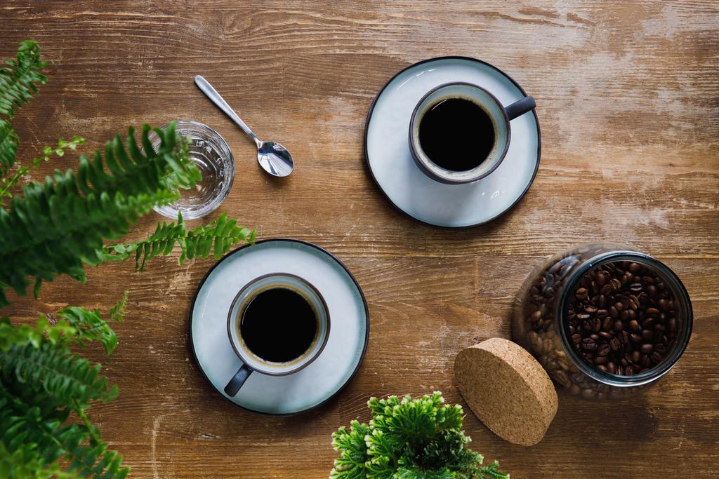 Πρωί μαύρο καφέ σε φλιτζάνια στο τραπέζι με φυτά σε καφενείο - Φωτογραφία, εικόνα